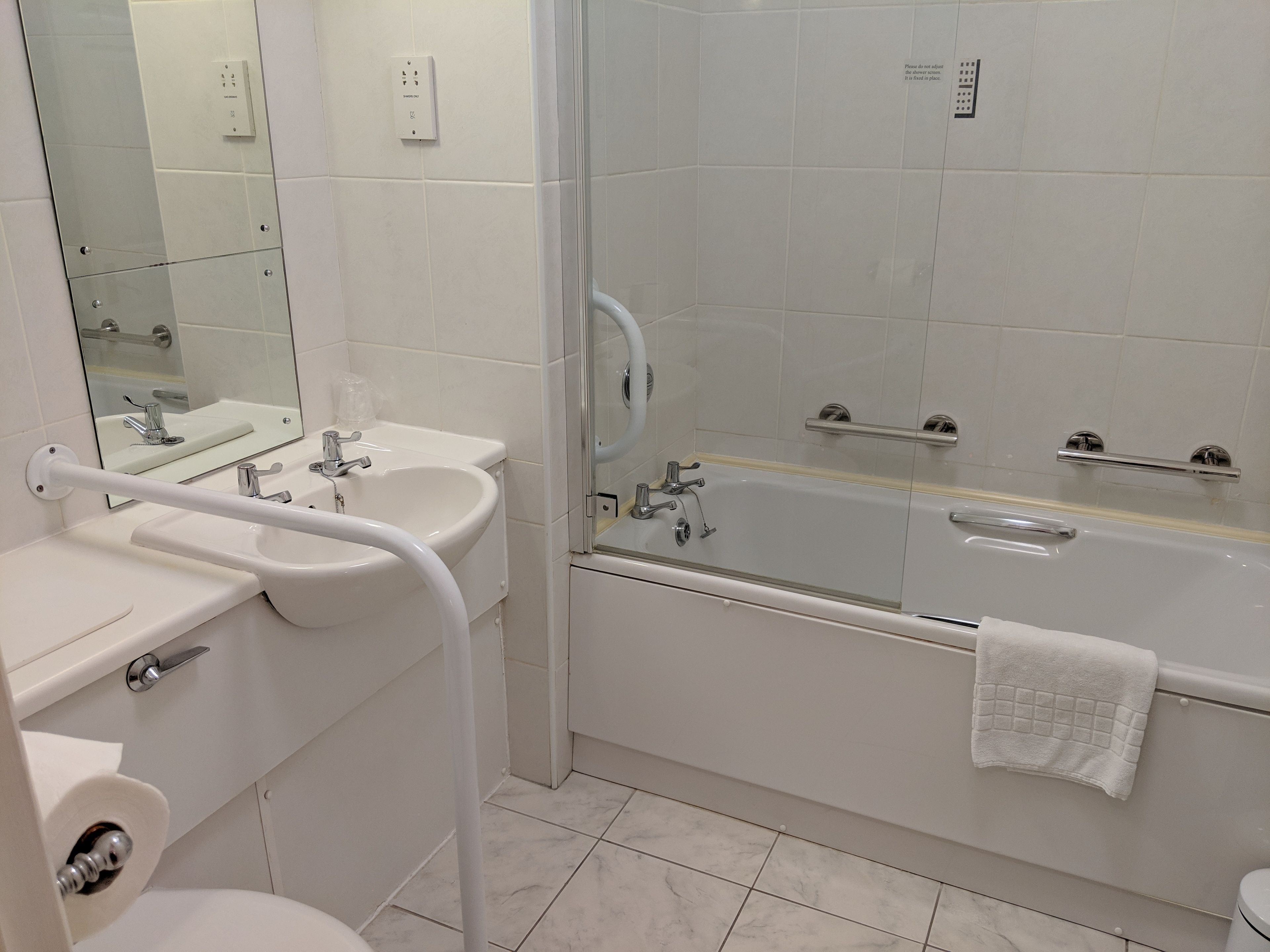 A modern bathroom with a sink, mirror, toilet, and bathtub.
