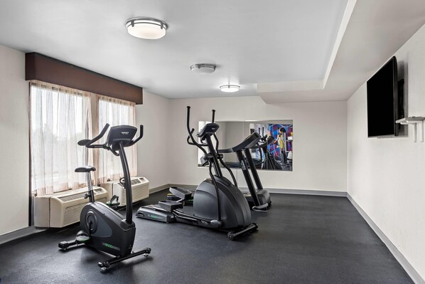 A gym with two elliptical machines, a stationary bike, and a large mirror.