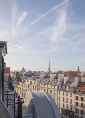 A rooftop terrace with a view of the Eiffel Tower and surrounding buildings. - Hotel Montalembert (Paris)