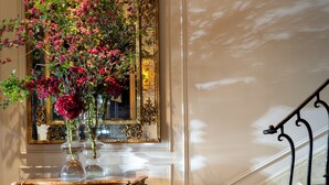 A grand staircase with ornate railings, a marble floor, and a decorative console table with a vase of flowers. - Hotel Montalembert (Paris)