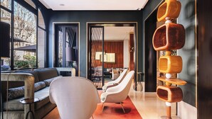 A modern interior with a sofa, chairs, a red carpet, and a unique wooden sculpture. - Hotel Montalembert (Paris)