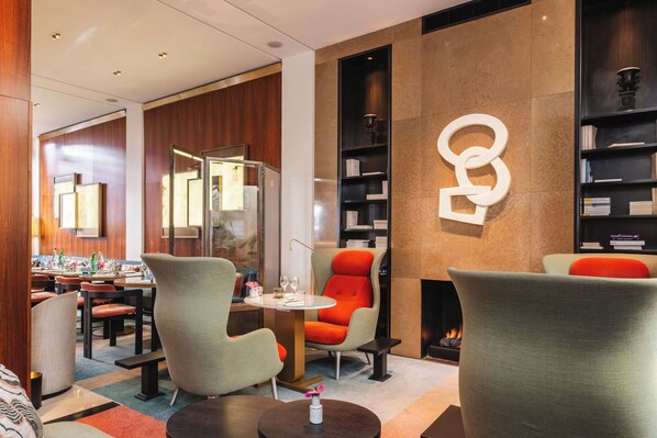 A modern lobby with seating, a fireplace, and a bookshelf.