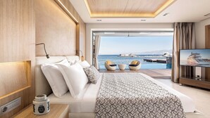 Un dormitorio moderno con una cama grande, televisión y vista al mar.