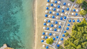 Vista aérea de una playa con hileras de sombrillas y un mar azul cristalino.