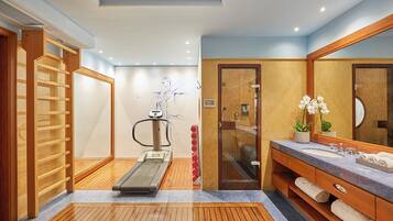 Un baño moderno con suelo de madera, cinta de correr, cabina de ducha de vidrio y tocador con un espejo grande.