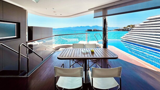 Un comedor moderno con una mesa y sillas, con vista a una piscina y al mar.