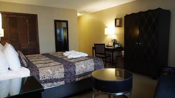 Una camera d'albergo con un letto, una scrivania, una sedia, un tavolino rotondo e un armadio.
