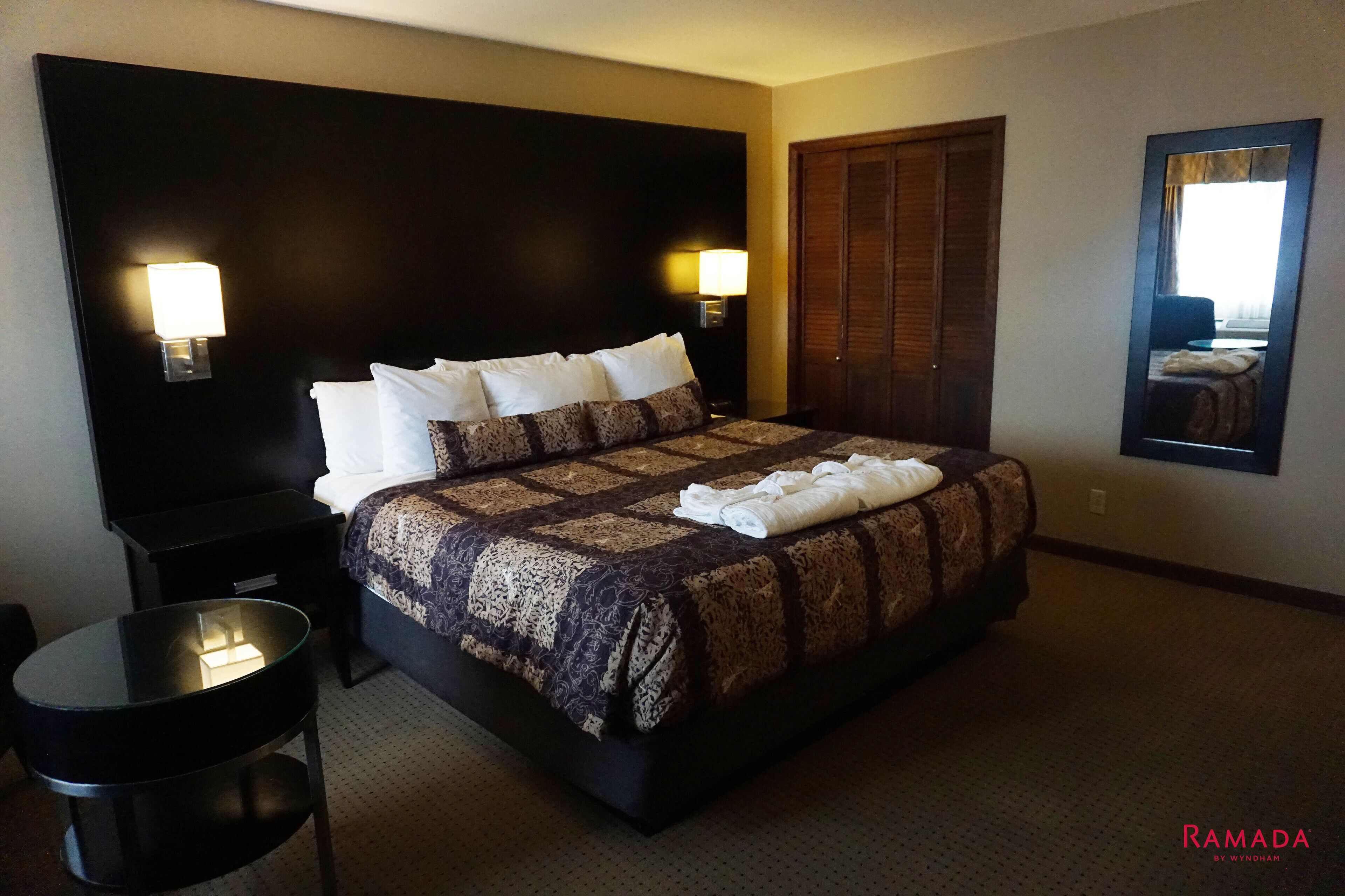A hotel room with a large bed, two bedside lamps, a round table, and a mirror on the wall.