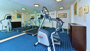 Un gimnasio con cintas de correr, elípticas y un espejo grande.