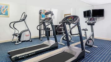 Une salle de sport équipée de tapis de course, d’une machine de musculation et d’un écran de télévision.