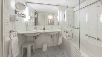 A modern bathroom with two sinks, a mirror, a toilet, and a glass-enclosed shower.
