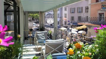Uma área de estar ao ar livre com mesas e cadeiras, um letreiro indicando terraço e vista para a rua.