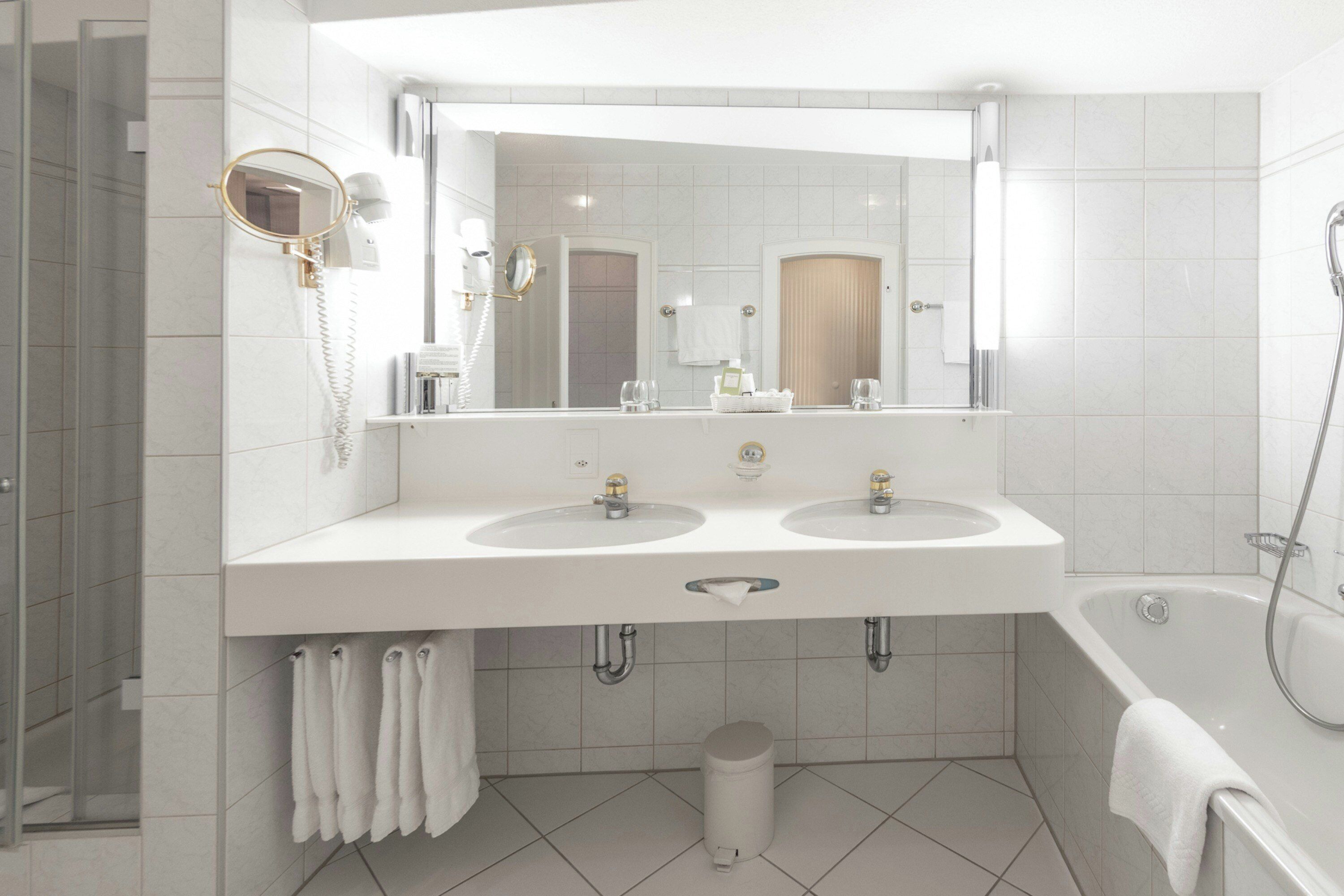 Un baño moderno con dos lavamanos, un espejo grande, ducha e inodoro.