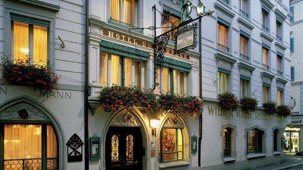 Un hôtel historique à l’architecture riche et élaborée, avec une entrée remarquable, une porte noire et des éléments décoratifs en fer forgé.