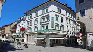 A historic hotel with a classic European facade, multiple balconies, and a central entrance with a red awning.