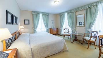 Habitación de hotel con una cama grande, un escritorio, una silla, una mesita y un espejo.