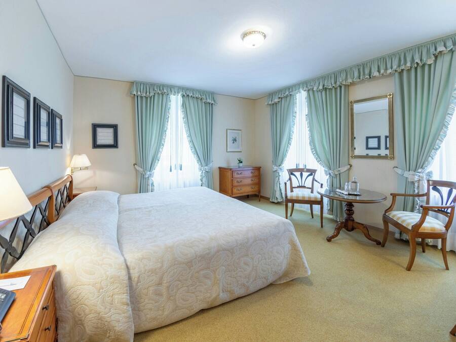 Habitación de hotel con una cama grande, un escritorio, una silla, una mesita y un espejo.