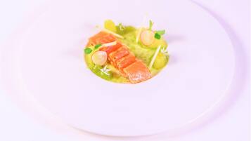 Un plato blanco con salsa verde, salmón, rábanos y una pequeña guarnición.