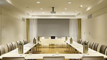 A conference room with a long table, chairs, a projector, and a screen.