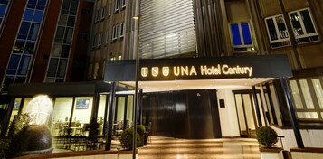 Η είσοδος του ξενοδοχείου UNA Hotel Century, με τη μοντέρνα πρόσοψη, τα μεγάλα παράθυρα και τον καλά φωτισμένο χώρο υποδοχής.
