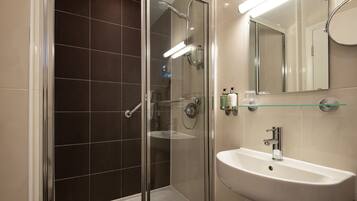 A modern bathroom with a glass-enclosed shower, a white sink, and a mirror above it.