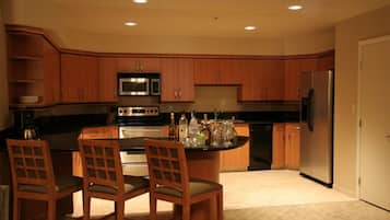 A modern kitchen with wooden cabinets, stainless steel appliances, and a central island with bar stools.