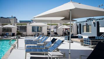 A poolside area with sun loungers, umbrellas, and a pool.