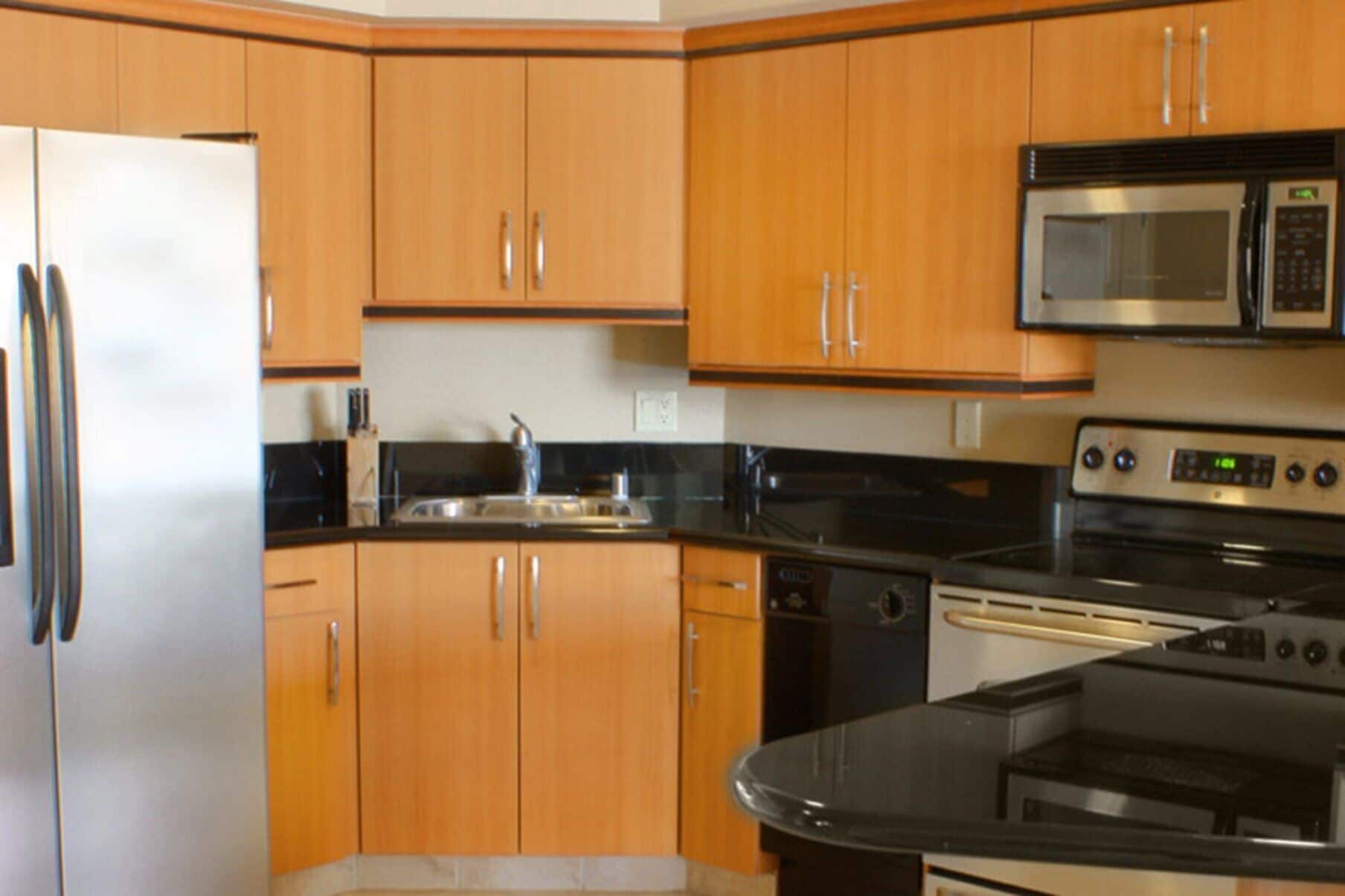 A kitchen with wooden cabinets, a stainless steel refrigerator, a microwave, an oven, and a dishwasher.