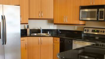 A kitchen with wooden cabinets, a stainless steel refrigerator, a microwave, an oven, and a dishwasher.