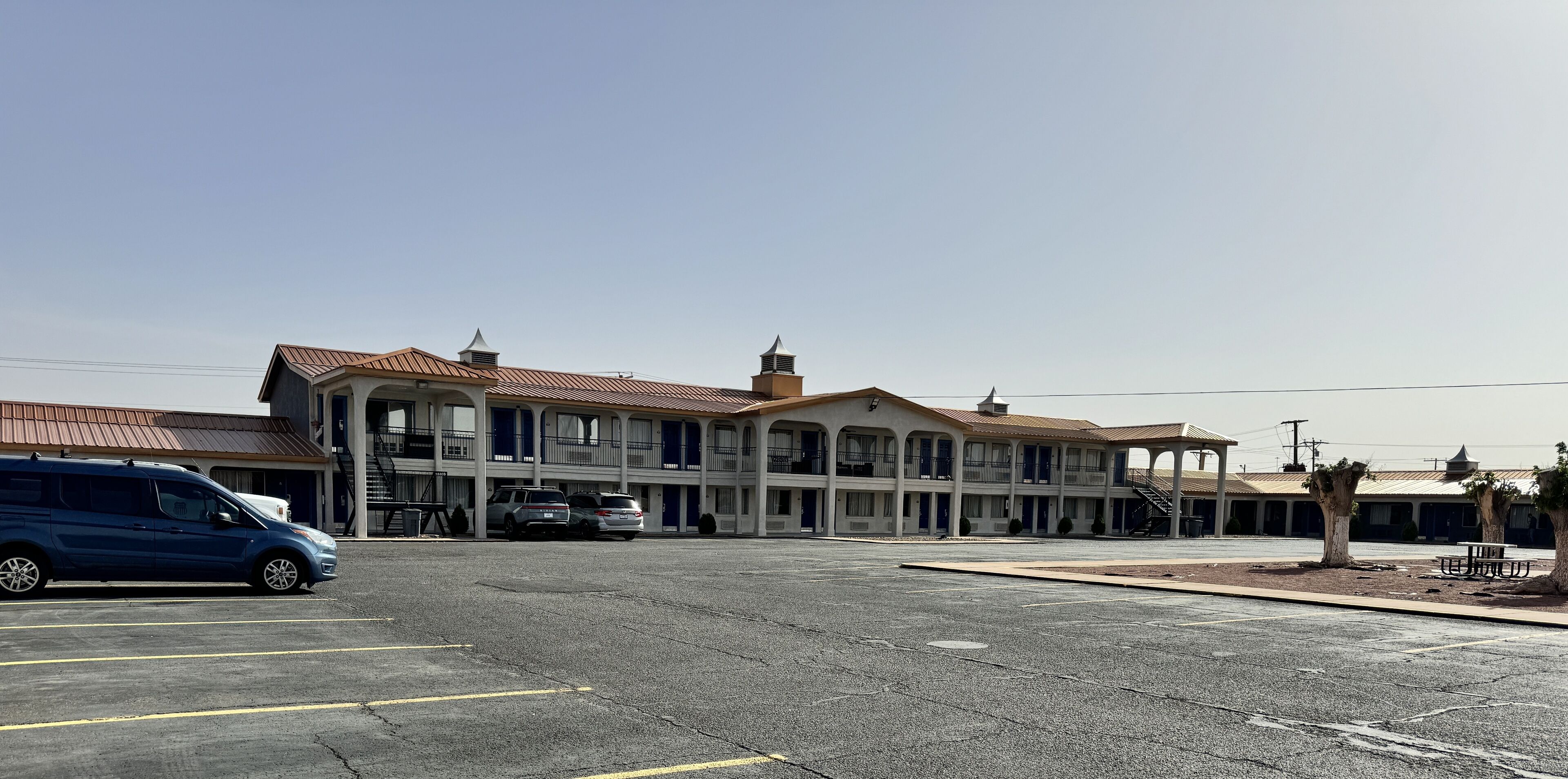 A motel with a central courtyard, multiple balconies, and a parking lot.