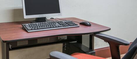 Uma mesa de escritório com monitor, teclado e rato.
