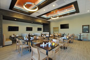 A restaurant with multiple tables and booths, ceiling lights, and a menu board on the wall. - Holiday Inn Hattiesburg - North by IHG (Hattiesburg)