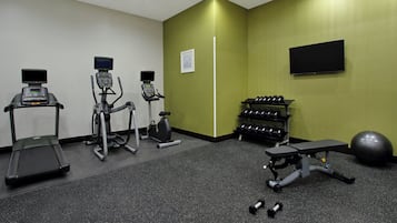 Ein Fitnessraum mit Laufbändern, Crosstrainern, einer Bank, Kurzhanteln und einem Ergometer.
