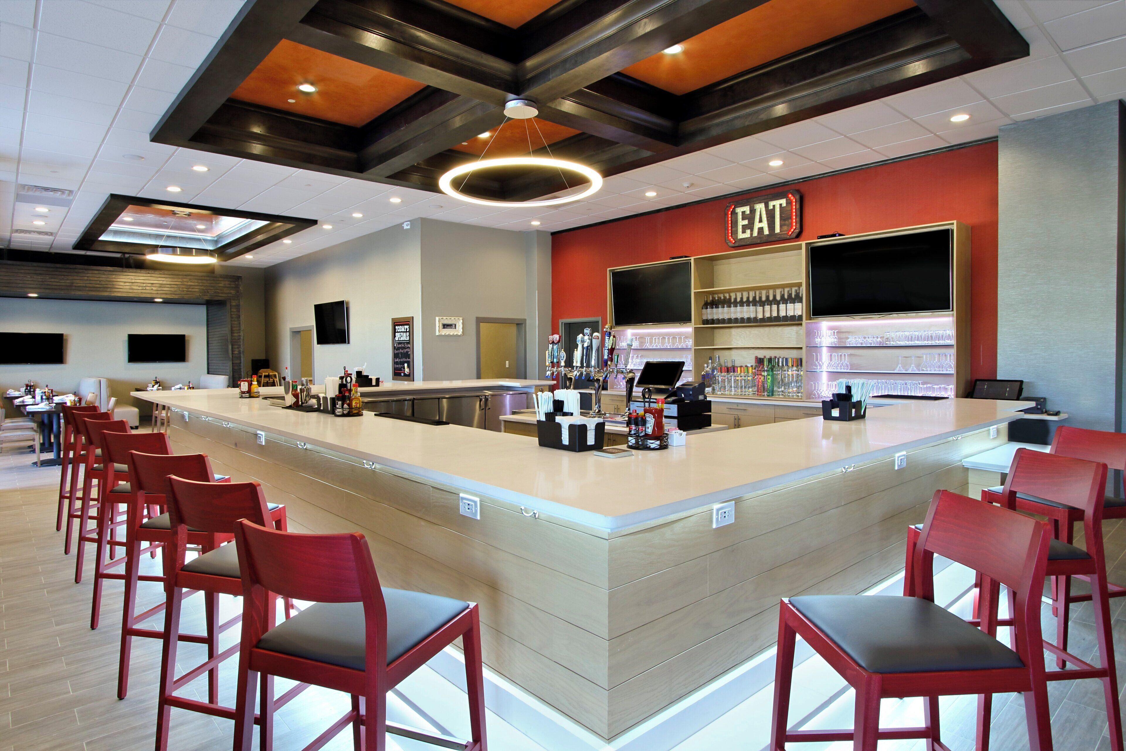 A bar area with a counter, red chairs, and a sign that reads 'EAT'.