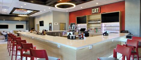 A bar area with a counter, red chairs, and a sign that reads 'EAT'.