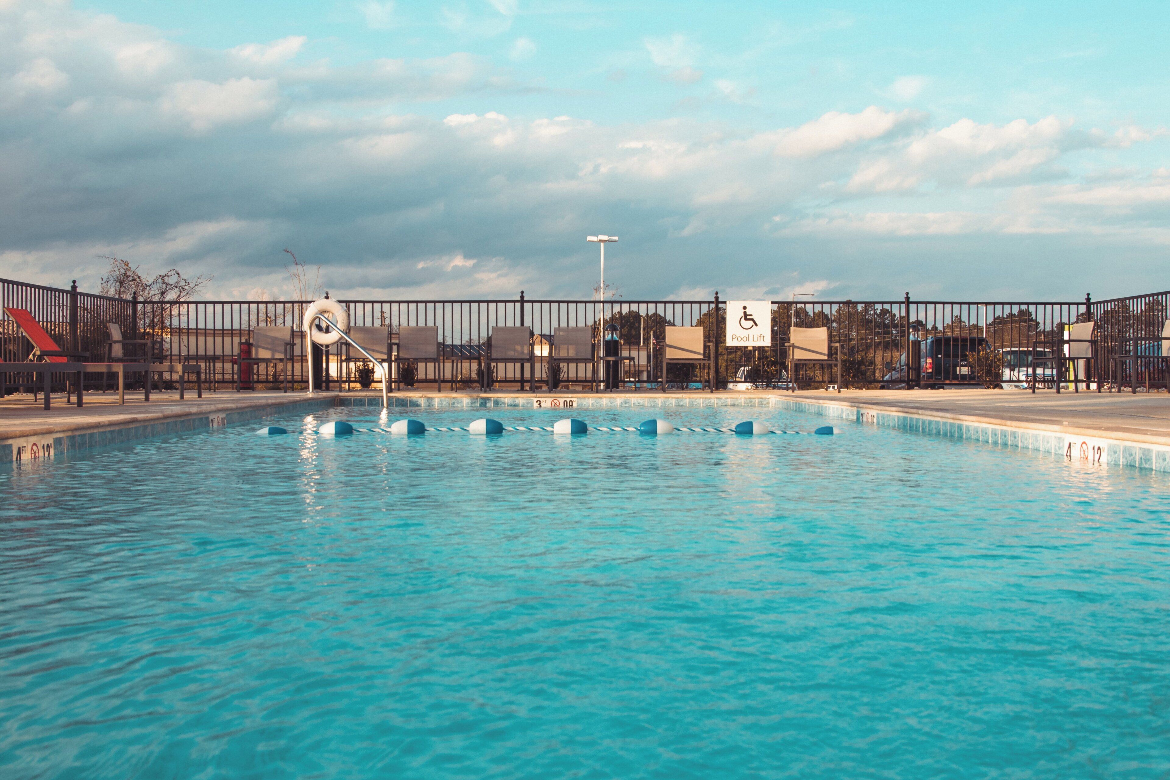 A swimming pool with a fence, a lifeguard stand, and a sign indicating a pool lift.