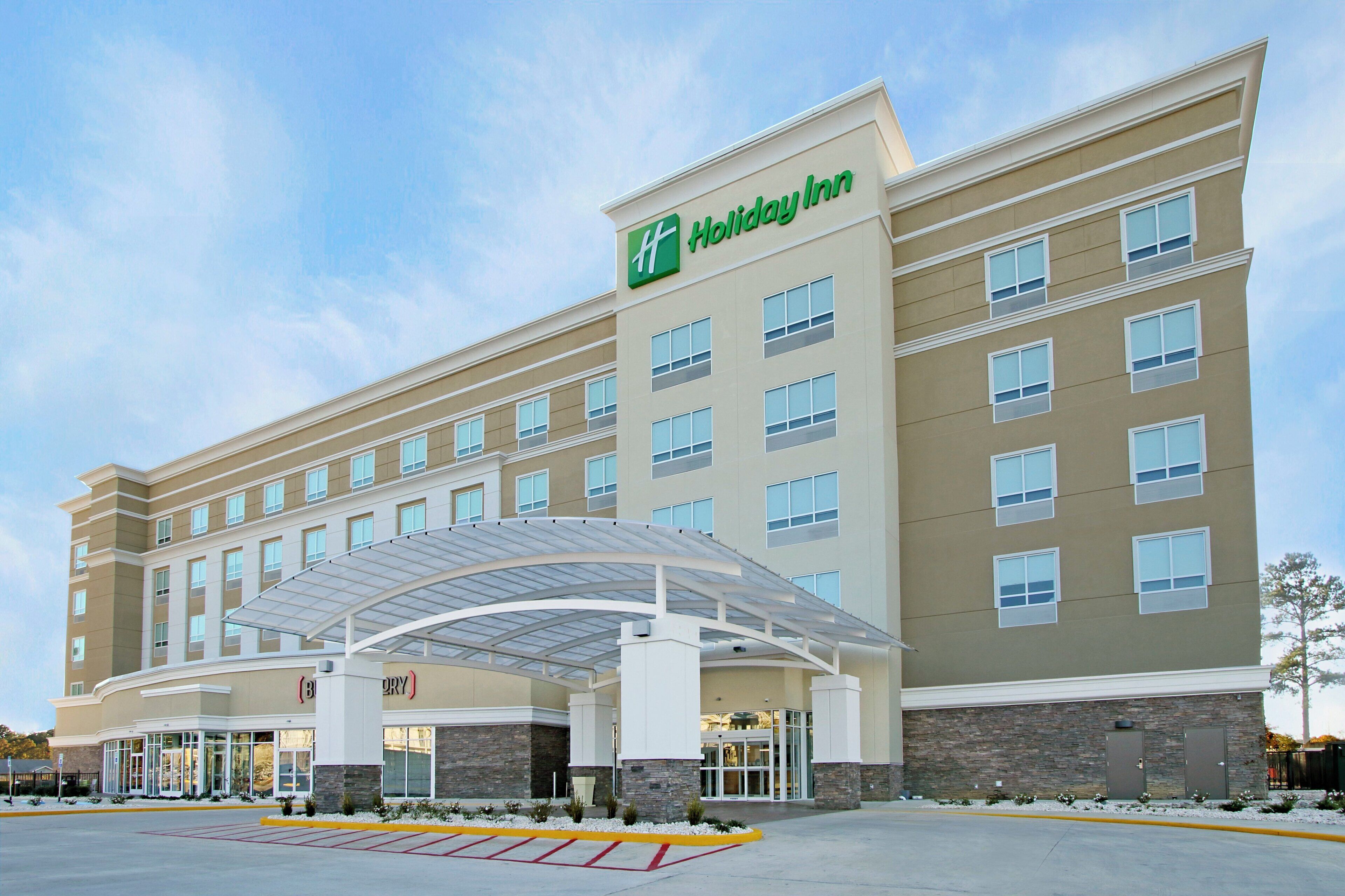 A Holiday Inn hotel with a covered entrance, multiple floors, and a parking lot.