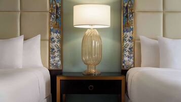 A hotel room with a bed, a nightstand with a lamp, and a decorative mirror.