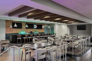 Een modern restaurant met een bakstenen muur, een bar en meerdere eettafels met stoelen.
