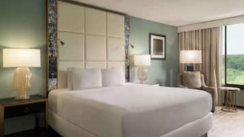 A hotel room with a large bed, two bedside tables with lamps, a chair, and a window with curtains.