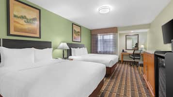 A hotel room with two beds, a desk, a chair, a TV, and artwork on the walls.