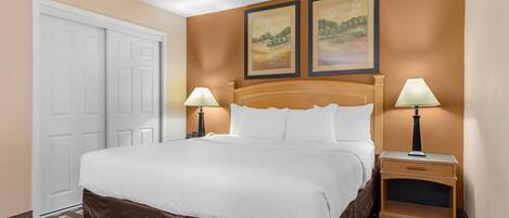 A neatly made bed with white linens, two bedside lamps, and a nightstand with a lamp.