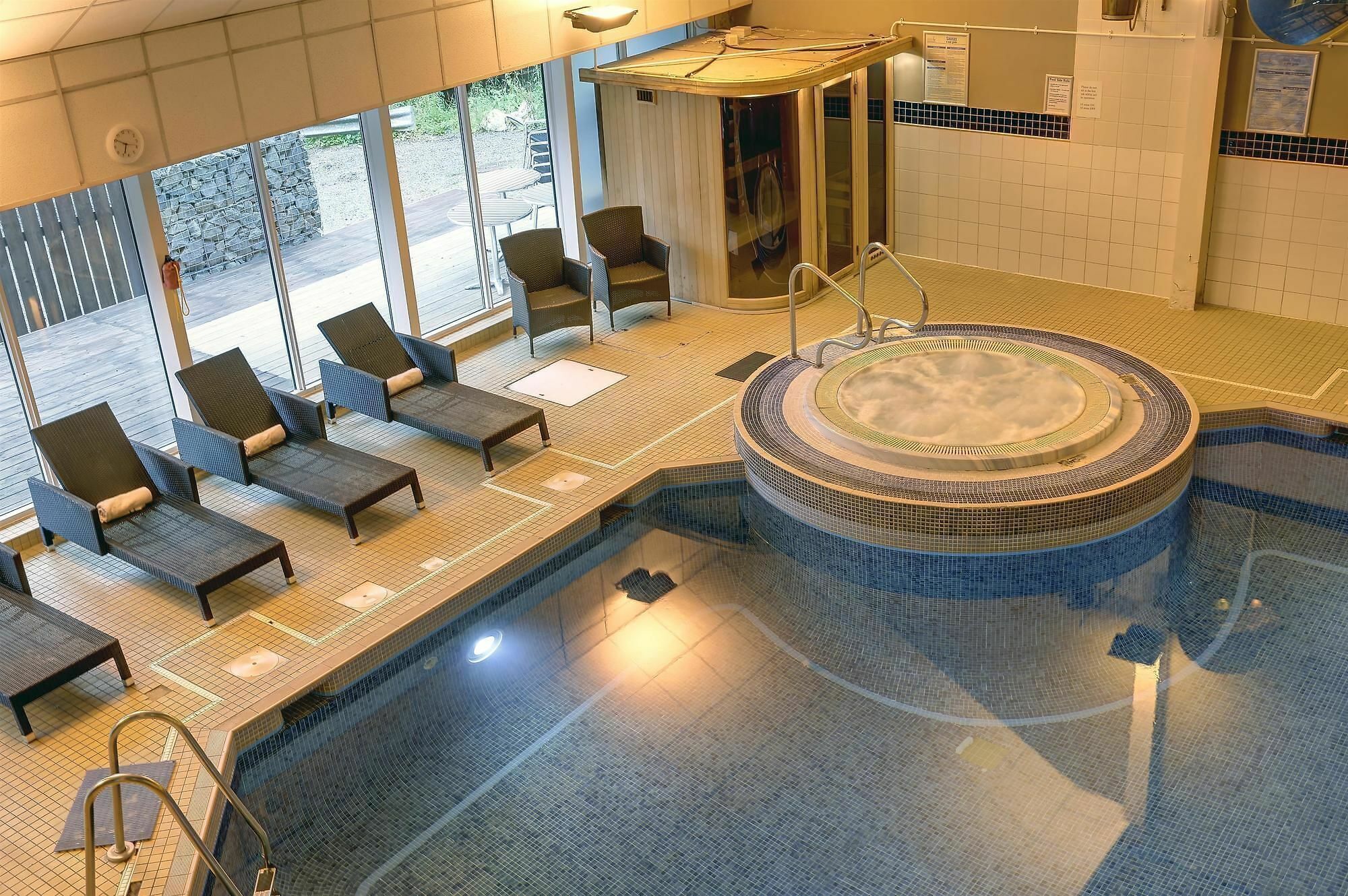 A pool area with lounge chairs, a hot tub, and a covered seating area.