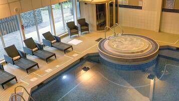 A pool area with lounge chairs, a hot tub, and a covered seating area.