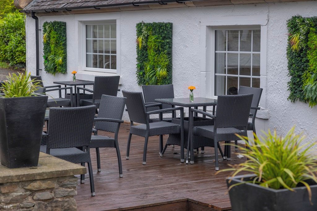 An outdoor seating area with wicker furniture and potted plants.