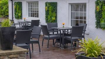 An outdoor seating area with wicker furniture and potted plants.