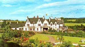 A large, white, multi-story building with a symmetrical facade, surrounded by well-maintained gardens and a clear sky. - Buchanan Arms Hotel & Leisure, Sure Hotel Collection (Drymen)