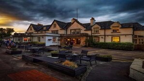 A traditional building with a central entrance, outdoor seating area, and a parking lot. - Buchanan Arms Hotel & Leisure, Sure Hotel Collection (Drymen)