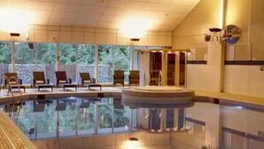 A large indoor swimming pool with clear water, surrounded by lounge chairs and a stone wall. - Buchanan Arms Hotel & Leisure, Sure Hotel Collection (Drymen)