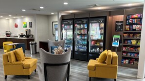 A hotel lobby with two yellow armchairs, a grey chair with a decorative pillow, and a self-checkout kiosk. - Quality Inn Placentia Anaheim Fullerton (Placentia)
